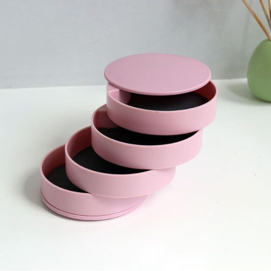 Rotating jewelry storage box with pink lid and layered velvet-lined compartments