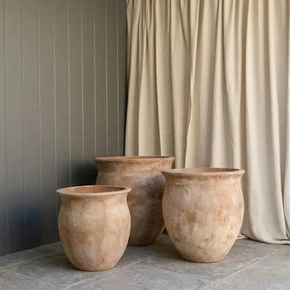 Three beige plant pots with wide flared rims, arranged without plants.
