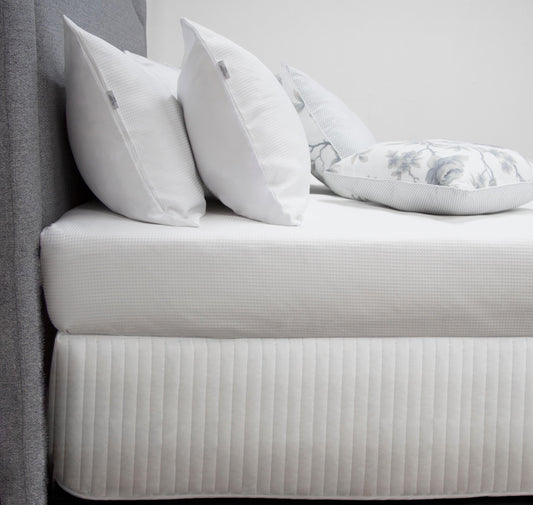 White quilted bed valance with vertical channel stitching along the top edge