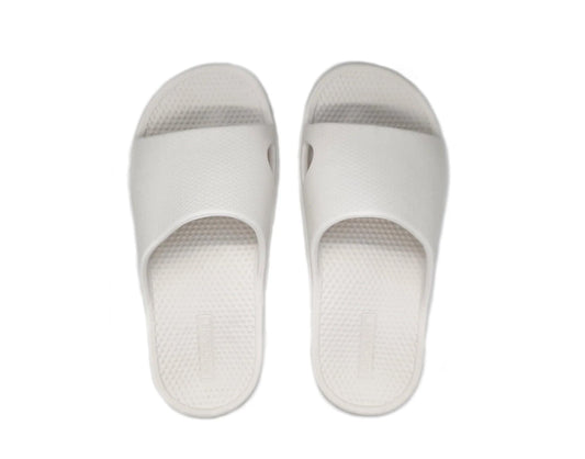 White slide sandals, front view: textured sole and cushioned toe strap.