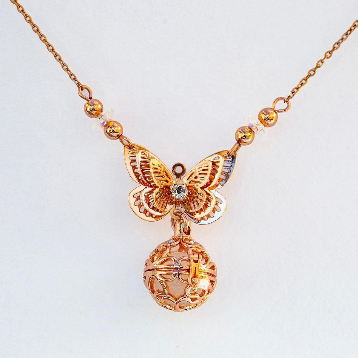 Rose-gold butterfly charm necklace with heart-shaped diffuser locket and glowing bead accents