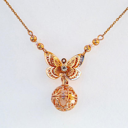 Rose-gold butterfly charm necklace with heart-shaped diffuser locket and glowing bead accents