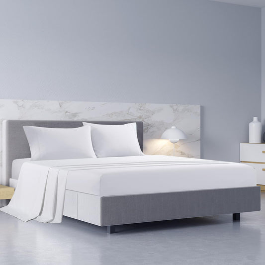 White king bed sheet set with pillowcases on a gray upholstered bed frame