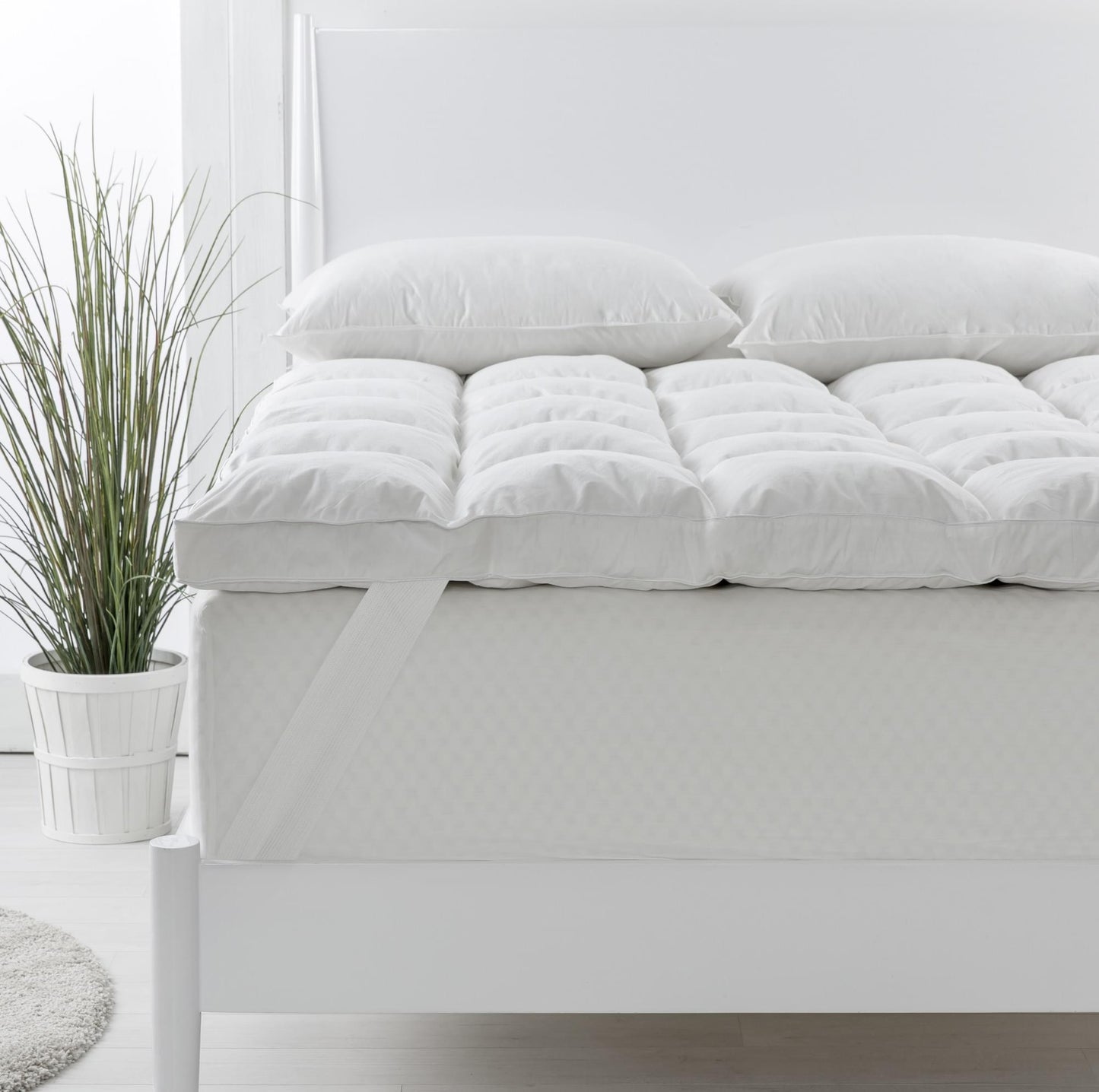 Single white duck down topper with two matching pillows on a bed