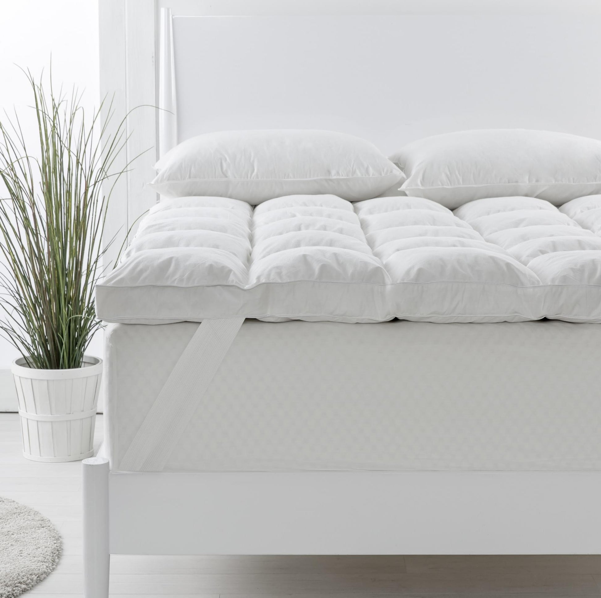 Single white duck down topper with two matching pillows on a bed