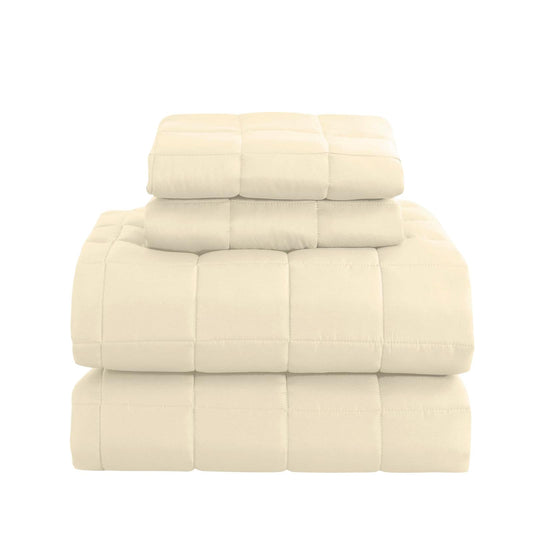 Light beige quilted coverlet set with matching shams, folded and stacked