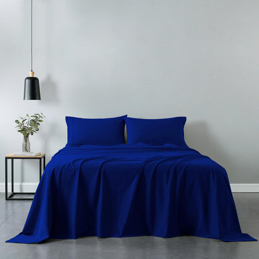 Royal blue sheet set with two pillowcases and draped fitted and flat sheets on bed