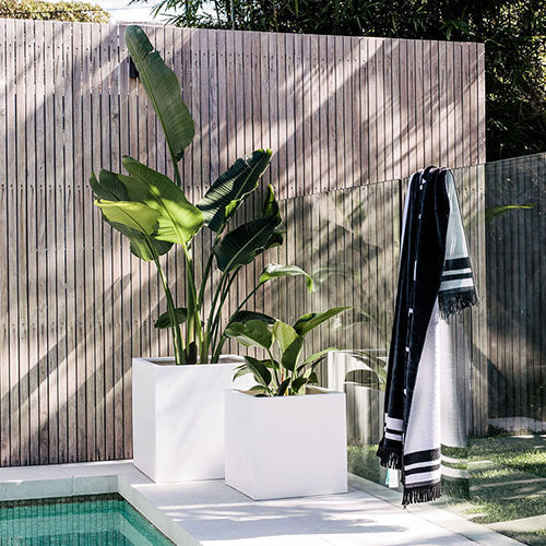 Rubix white square planters set of three with leafy plants beside a striped towel