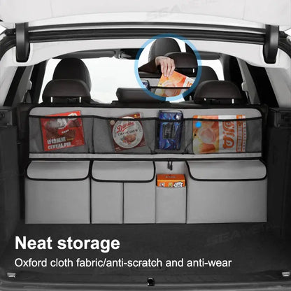 Gray car seat back organizer mounted behind seats with several zippered compartments