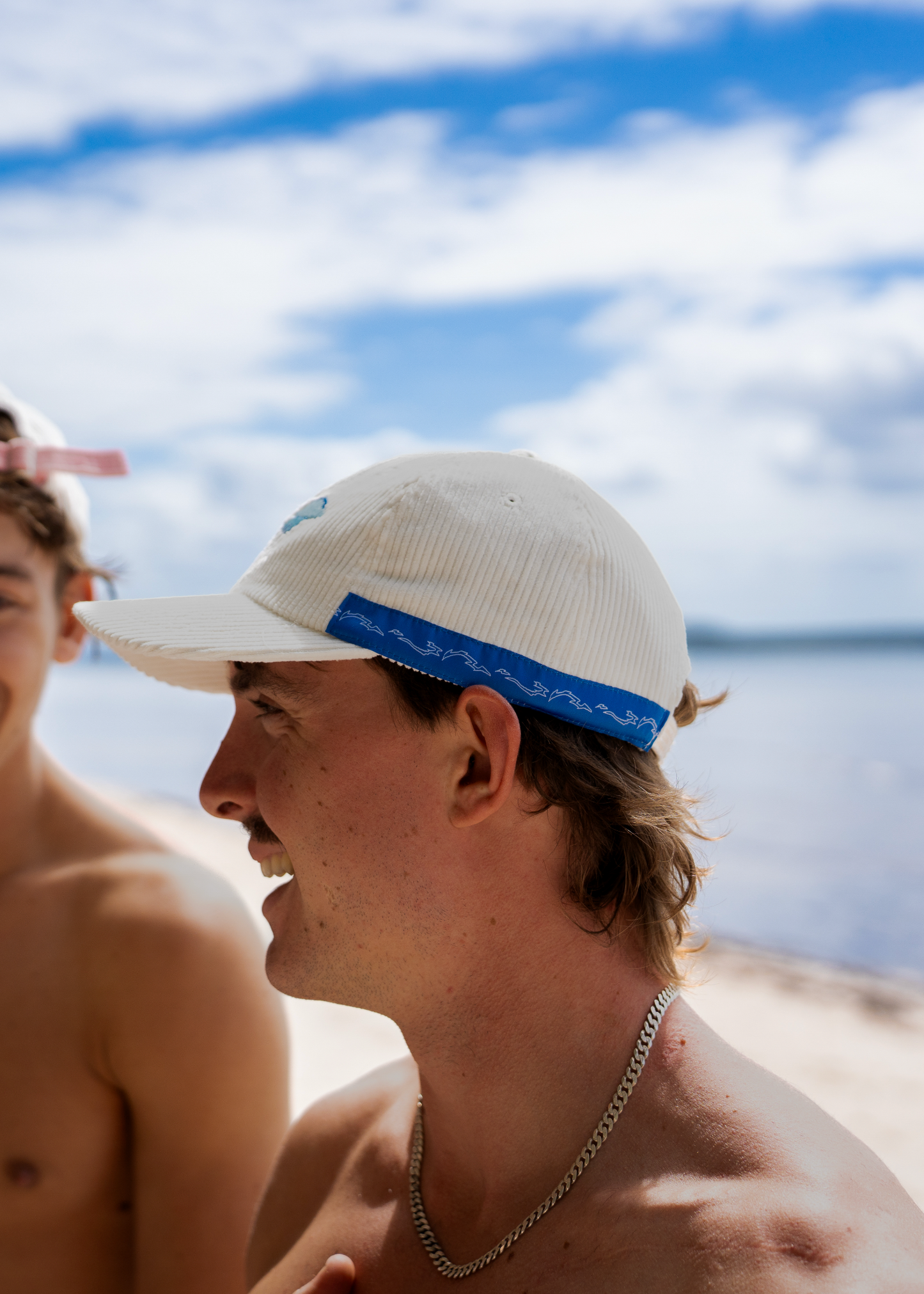 White cap with blue embroidered jellyfish on front, blue band detail at sides.