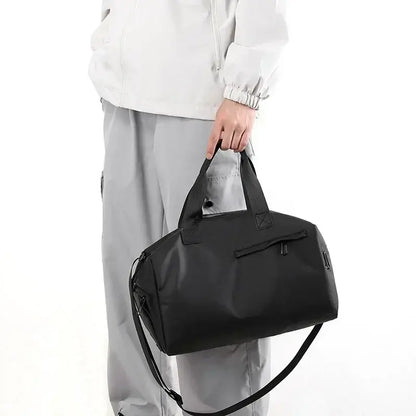 Black duffel gym bag carried by handles with adjustable shoulder strap