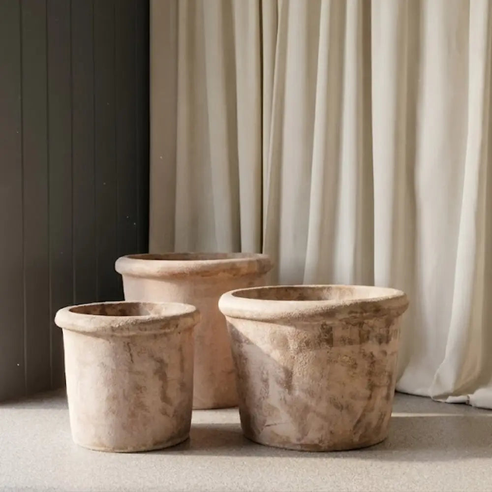 Group of three concrete planter pots in light beige, squat conical style.