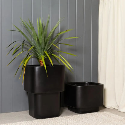 Black stacked cube planters set with long, spiky grass plant