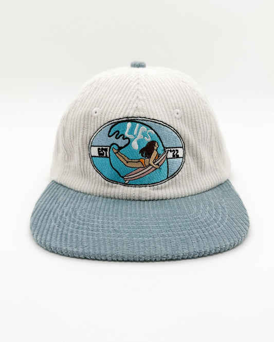 Two-tone knit cap with light blue brim and embroidered ocean surfer patch