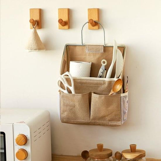 Wall-mounted storage bag with hanging handle and multiple organizer pockets, tan.