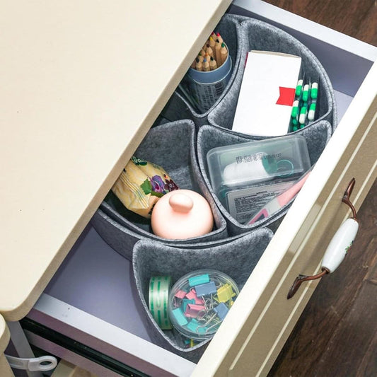 Gray felt drawer organizer with four sections holding cosmetics and small accessories