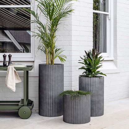 Concrete grey ribbed planters, three cylindrical pots with vertical fluted texture