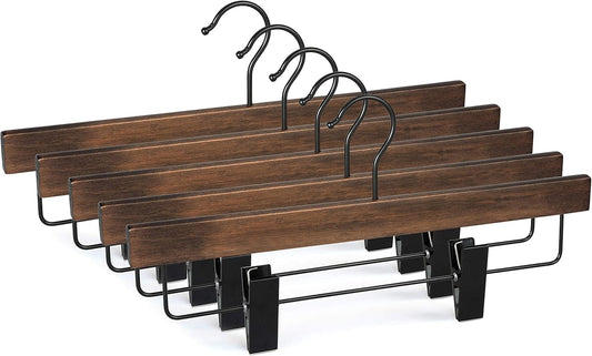 Three wooden pant hangers with black clips and curved hooks, dark finish.