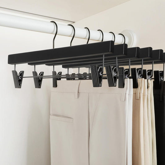 Black wooden pants hangers with spring clips on a closet rod