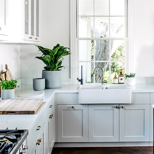 Grey planter pots on kitchen sink ledge, three containers with green plants