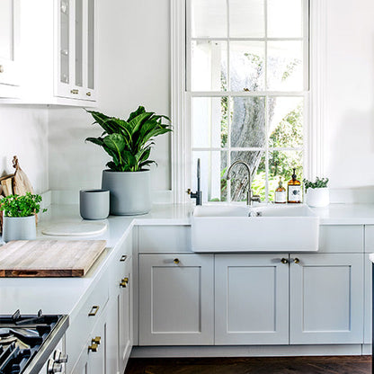 Grey planter pots on kitchen sink ledge, three containers with green plants