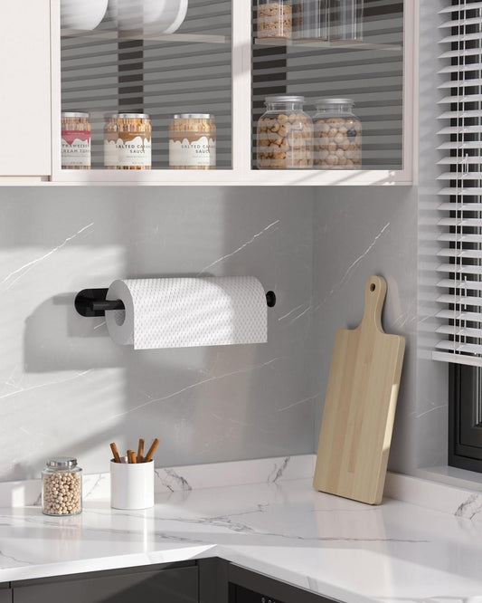 Black wall-mounted paper towel holder holding a white paper towel roll