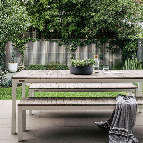 Tops Off planters on a patio bench with green plants in grey containers