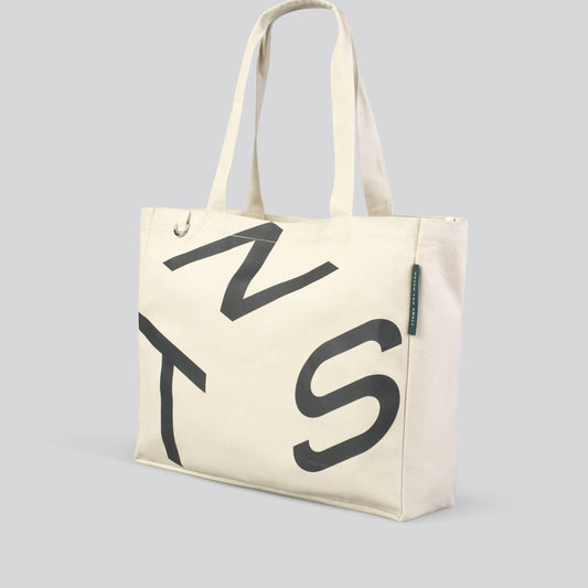 Cream canvas tote with bold black monogram lettering, open-top with side gusset