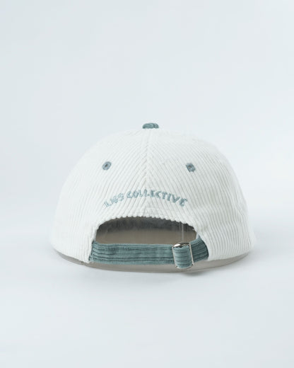 White ribbed mini lid cap with teal adjustable strap and embroidered logo on back