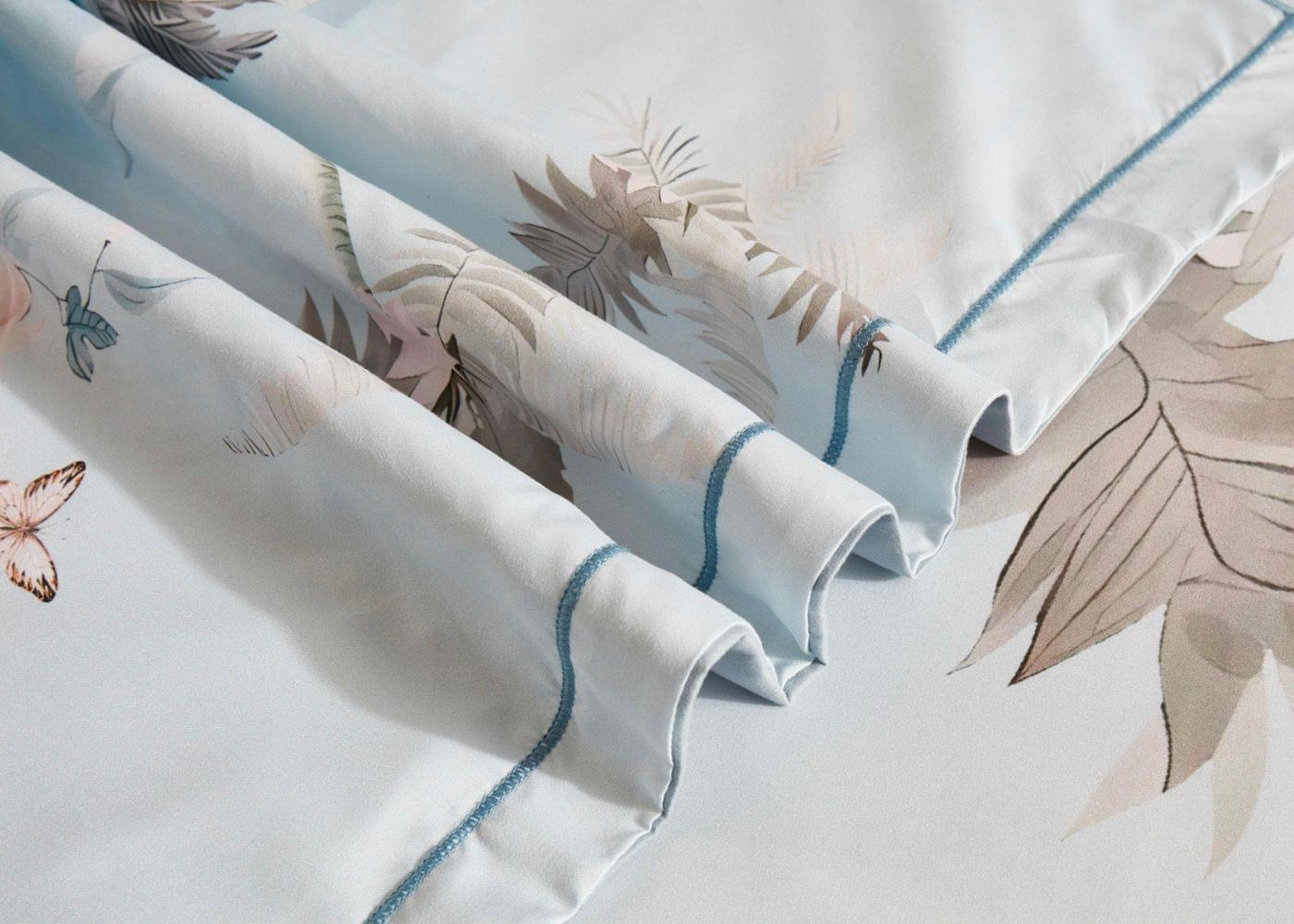 Tropical quilt cover fabric close-up with blue trim and palm leaf pattern