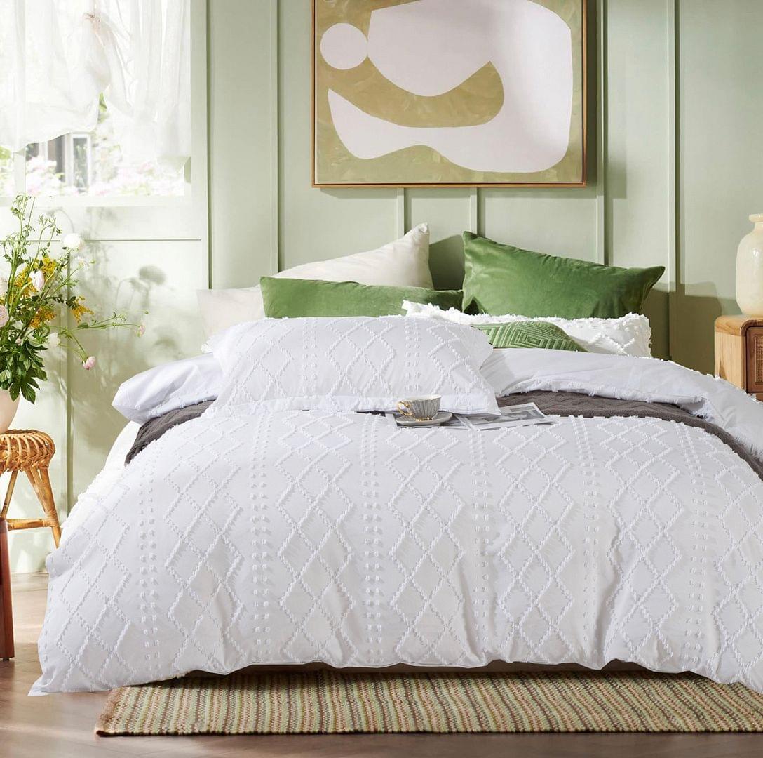 White quilt and pillow shams with diamond quilted texture on the bed