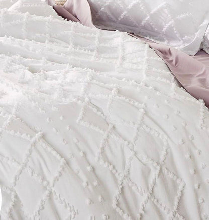 White quilt with raised tufted embroidery rows and looped tassel-like accents