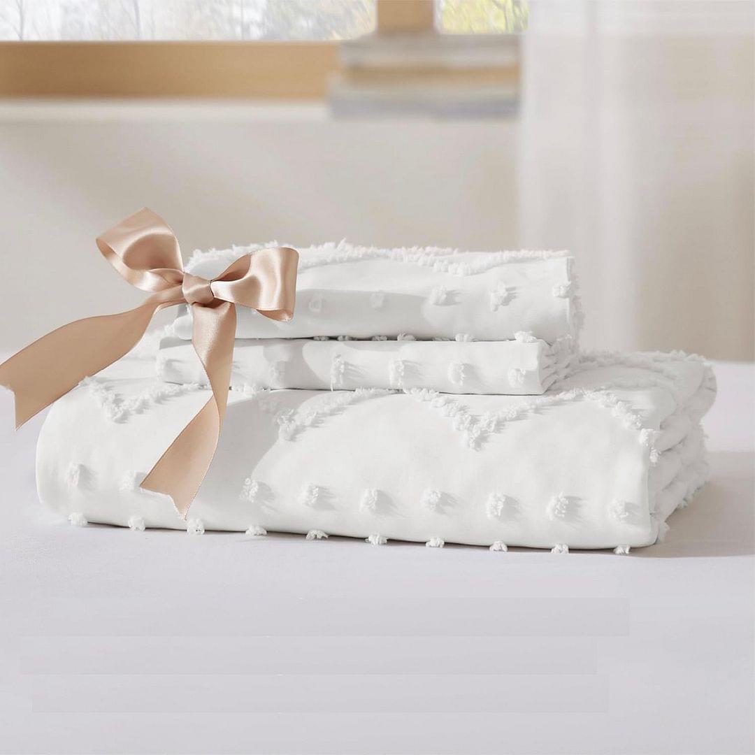 Folded white quilt set tied with a satin bow, showing tufted diamond stitching