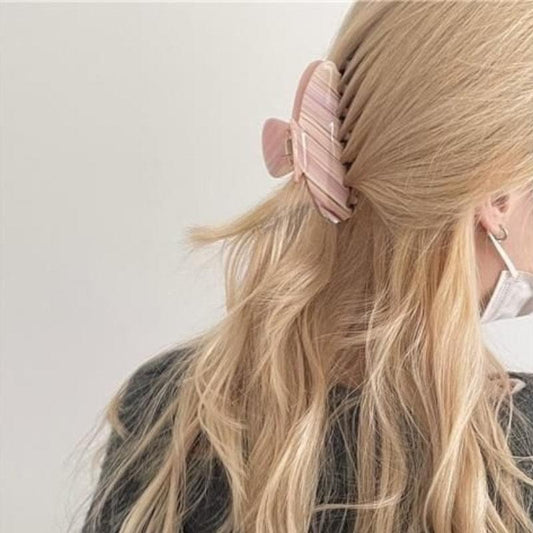 Large acetate hair claw clip with pink striped design, open clamp on hair.
