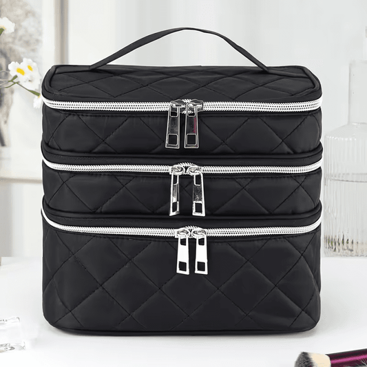 Black quilted cosmetic bag with three zip compartments, diamond pattern, top handle.
