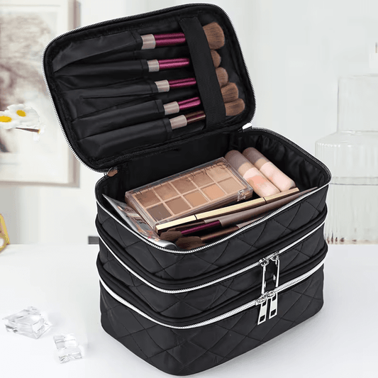 Open black quilted cosmetic bag with organizer pockets holding makeup palette and brushes
