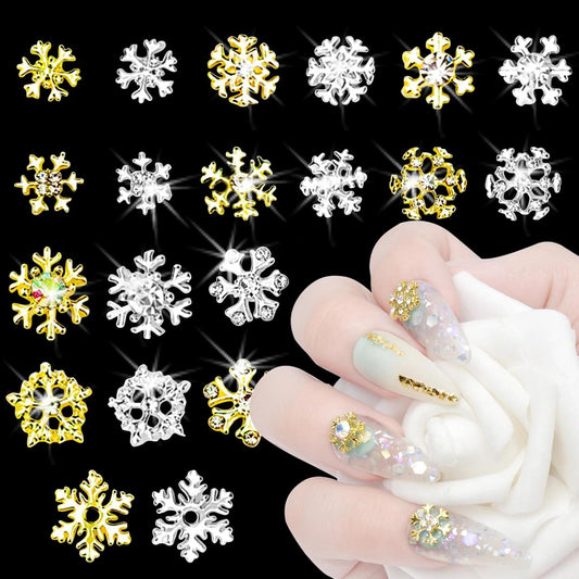 3D rhinestone snowflake nail charms in silver and gold, shown on decorated nails
