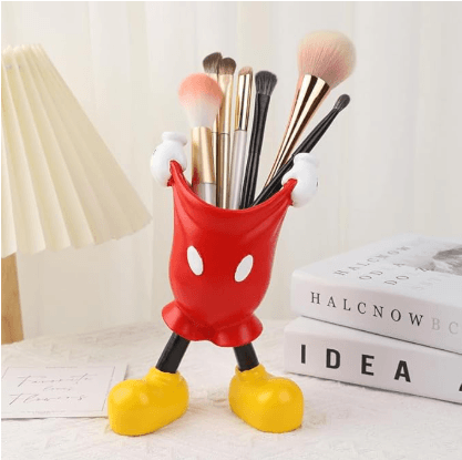 Red cat-shaped makeup brush holder with white arms, black legs, and yellow feet