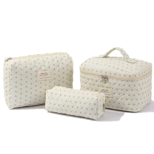Three cream floral quilted zippered toiletry pouches of different sizes, set of 3
