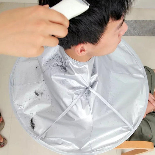 Grey hairdressing cape with neck tie, draped over shoulders and back.