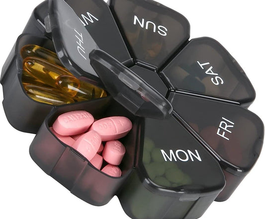 Black 7-day pill organizer with hinged day compartments, open to show pink pills