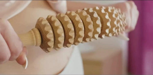 Wooden massage roller held against skin, close-up of textured rollers