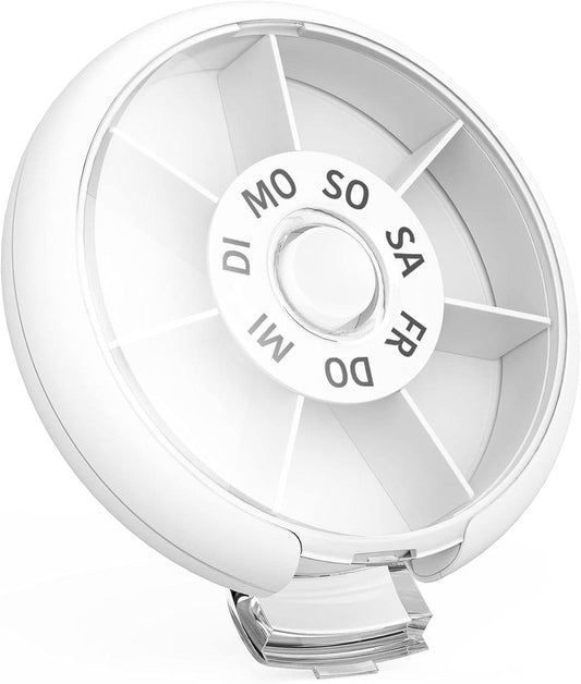 Open round white pill box showing inner weekly compartments and central day dial.