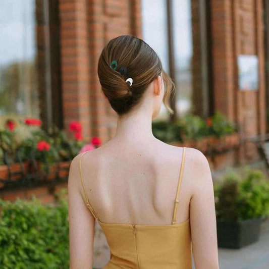 U-shaped hair clip securing a low bun with a dark green tone