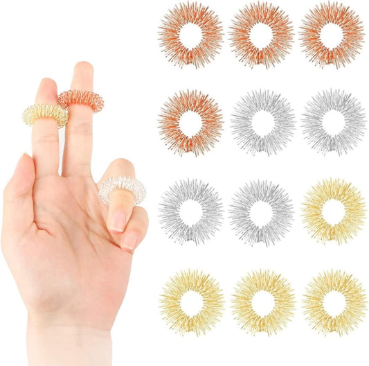 Finger massage rings on hand: gold and orange coiled spiked bands in open loops