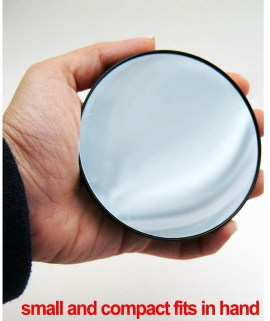 Round magnifying mirror with black rim held in a hand