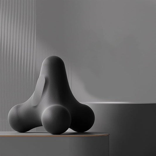 Dark three-ball massage device resting on a surface