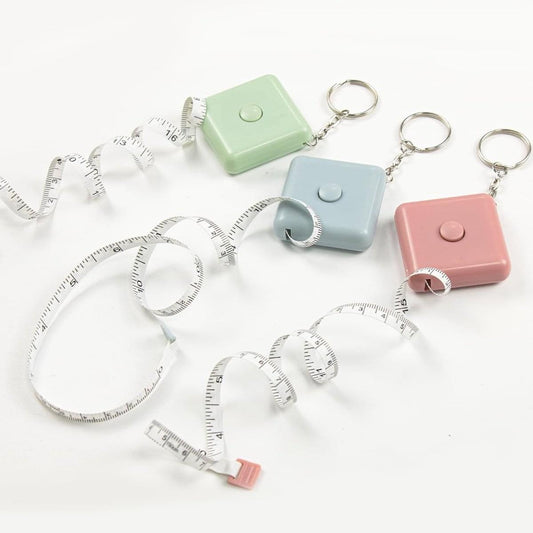 Extendable tape measures with white tapes and pastel keychain cases, set of three.