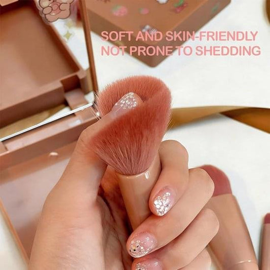 Mini makeup brush held in hand with soft dense bristles and metal handle