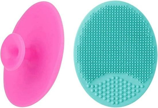 Two silicone facial cleansing brushes, pink and teal, round oval with massage dots
